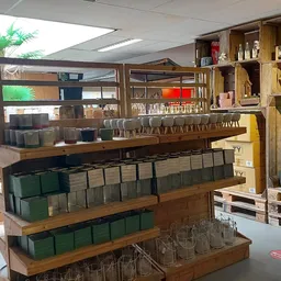 Houten display- en stellingen met diverse huishoudelijke artikelen zoals serviesgoed, kopjes en kasten in een kringloopwinkel