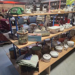 Houten tafels vol met tweedehands servies, huishoudwaar en decoratieve items