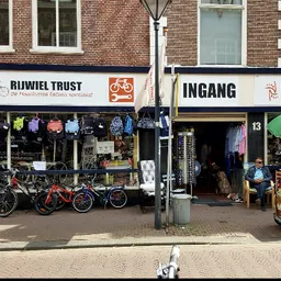 Gevel van kringloopwinkel aan straat met etalage vol spullen en fietsen buiten
