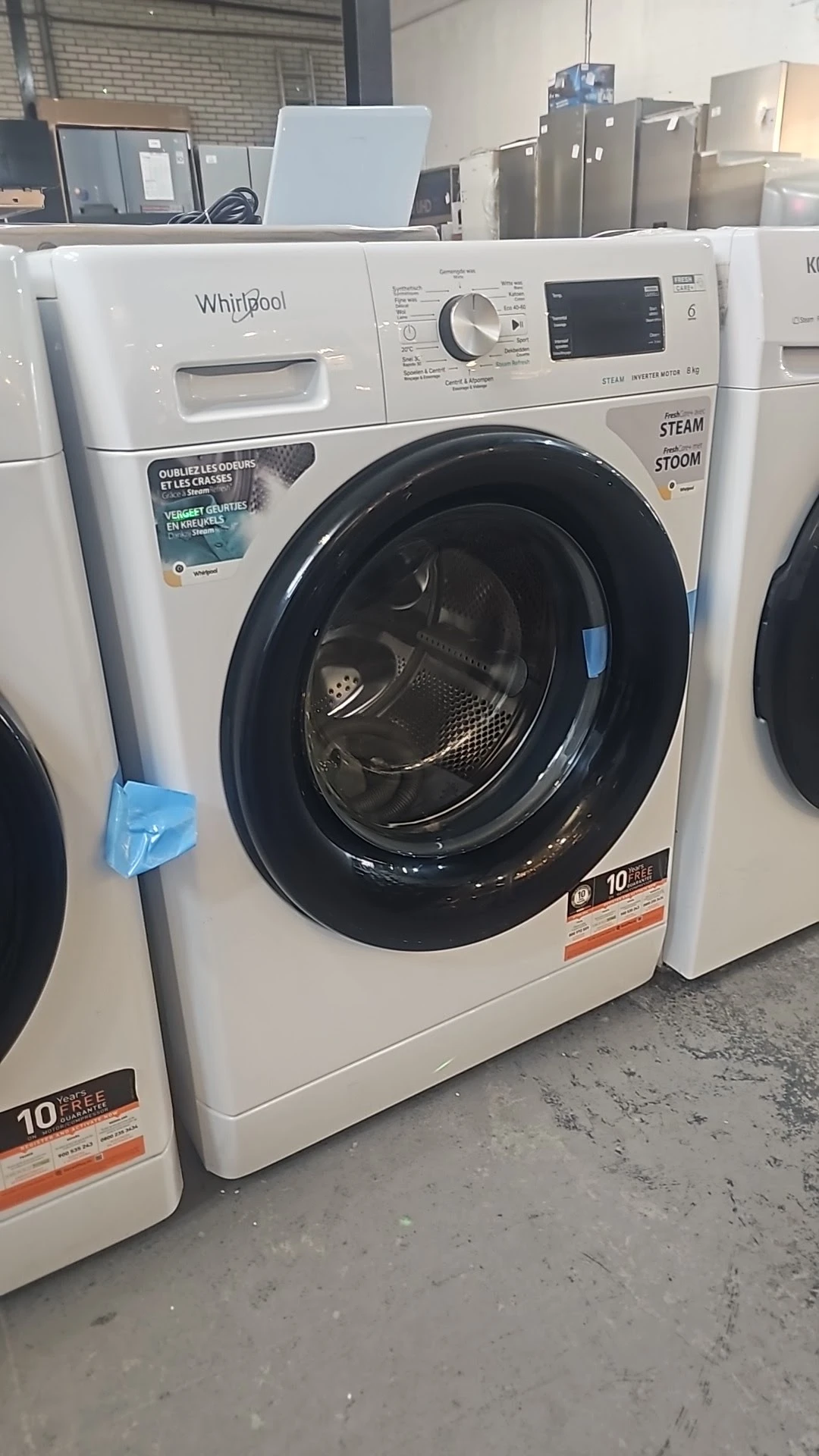 Witte wasmachine met zwarte deur en trommel, in showroommodeling in kringloopwinkel