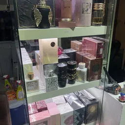 Glasvitrine met uitgestalde luxe artikelen: parfumflessen, sieraden en verpakte goederen op verschillende niveaus