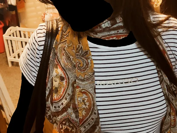 Tweedehands kleding op hangers, waaronder gestreepte en paisley-gemotiveerde kledingstukken
