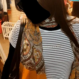 Tweedehands kleding op hangers, waaronder gestreepte en paisley-gemotiveerde kledingstukken