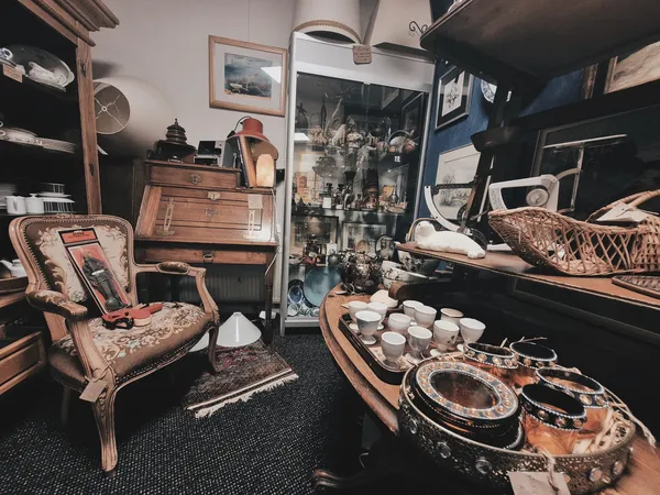 Interieur van kringloopwinkel met vintage meubels, serviesgoed, decoratie en spullen op stellingen