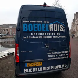 Bedrijfsbus van Boedelhuis woningontruiming met logo en contactgegevens, geparkeerd aan de straatkant