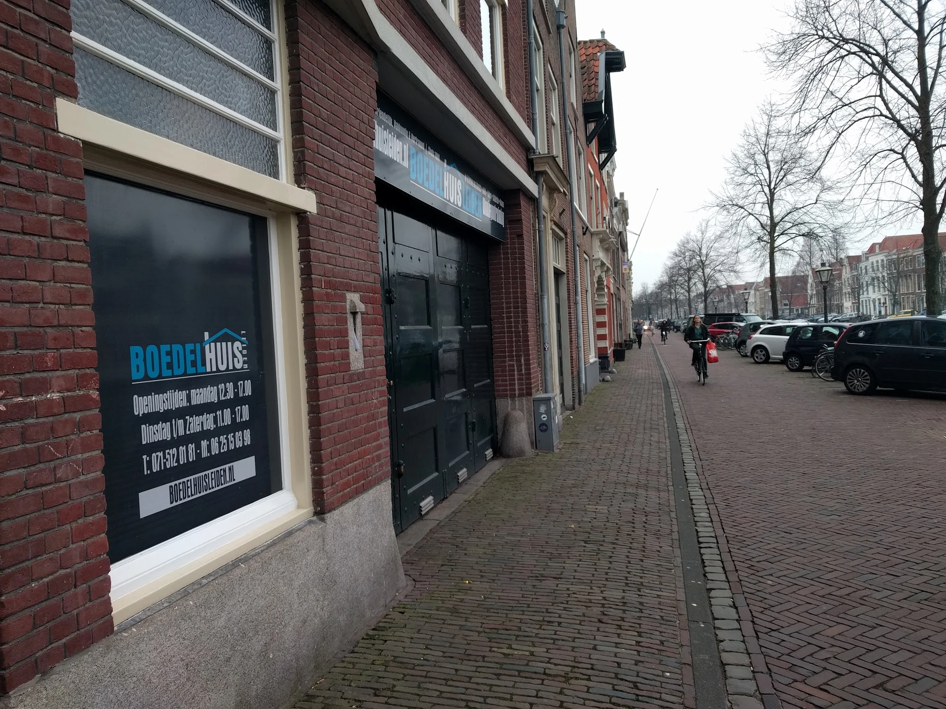 Gevel van kringloopwinkel aan Oude Vest in Leiden met blauwe winkelnaambord en zwarte deuren