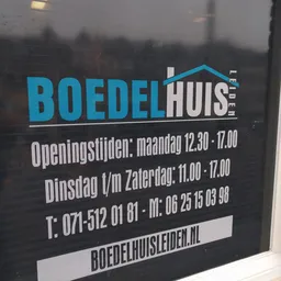 Zwart bord met blauwe en witte tekst met openingstijden en contactgegevens van een bedrijf