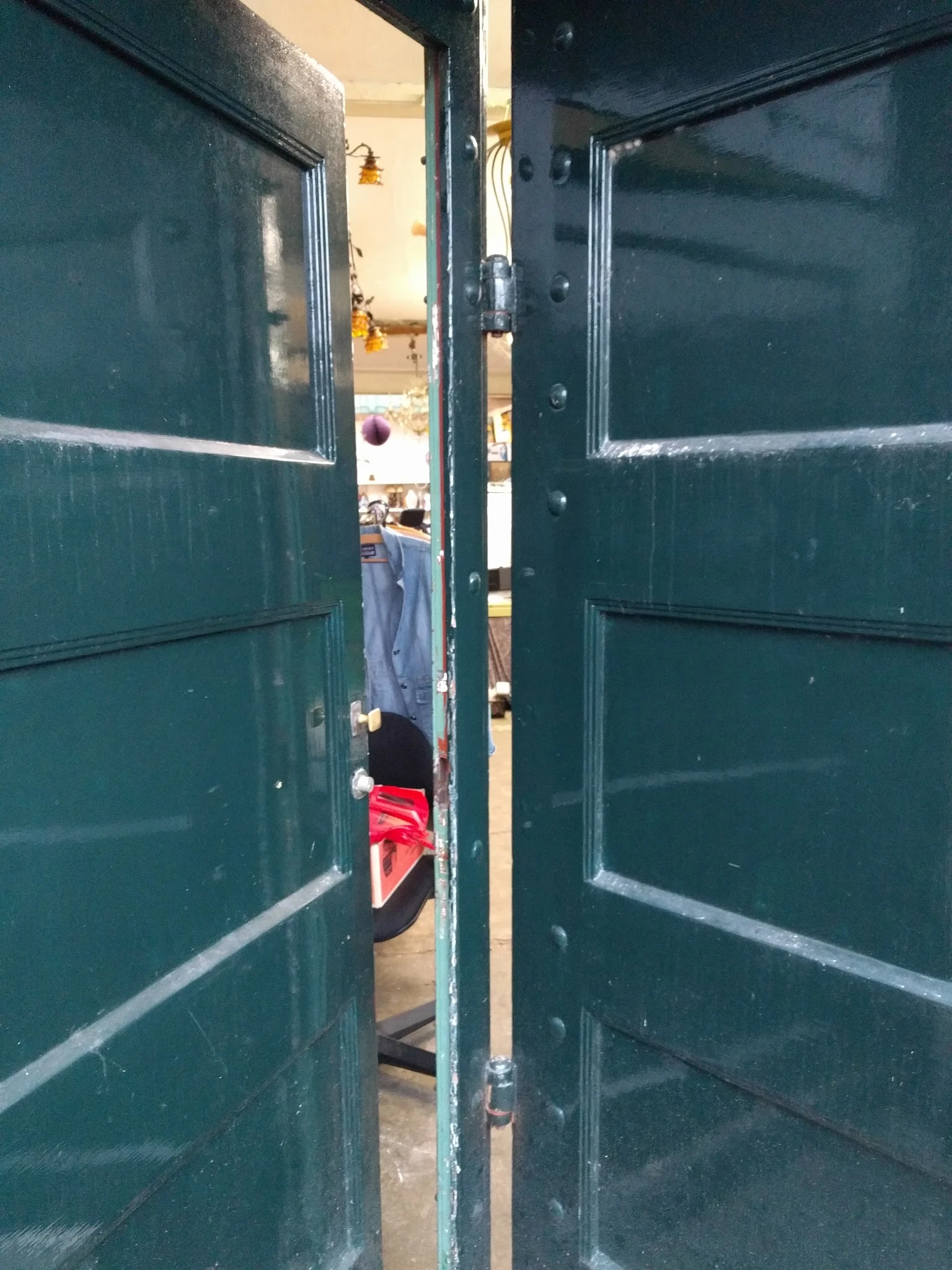 Zicht door openstaande deuren naar het interieur van een kringloopwinkel met kleding zichtbaar