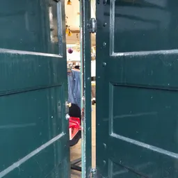 Zicht door openstaande deuren naar het interieur van een kringloopwinkel met kleding zichtbaar
