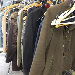 Rekken met tweedehands jassen en mantels in verschillende kleuren en materialen
