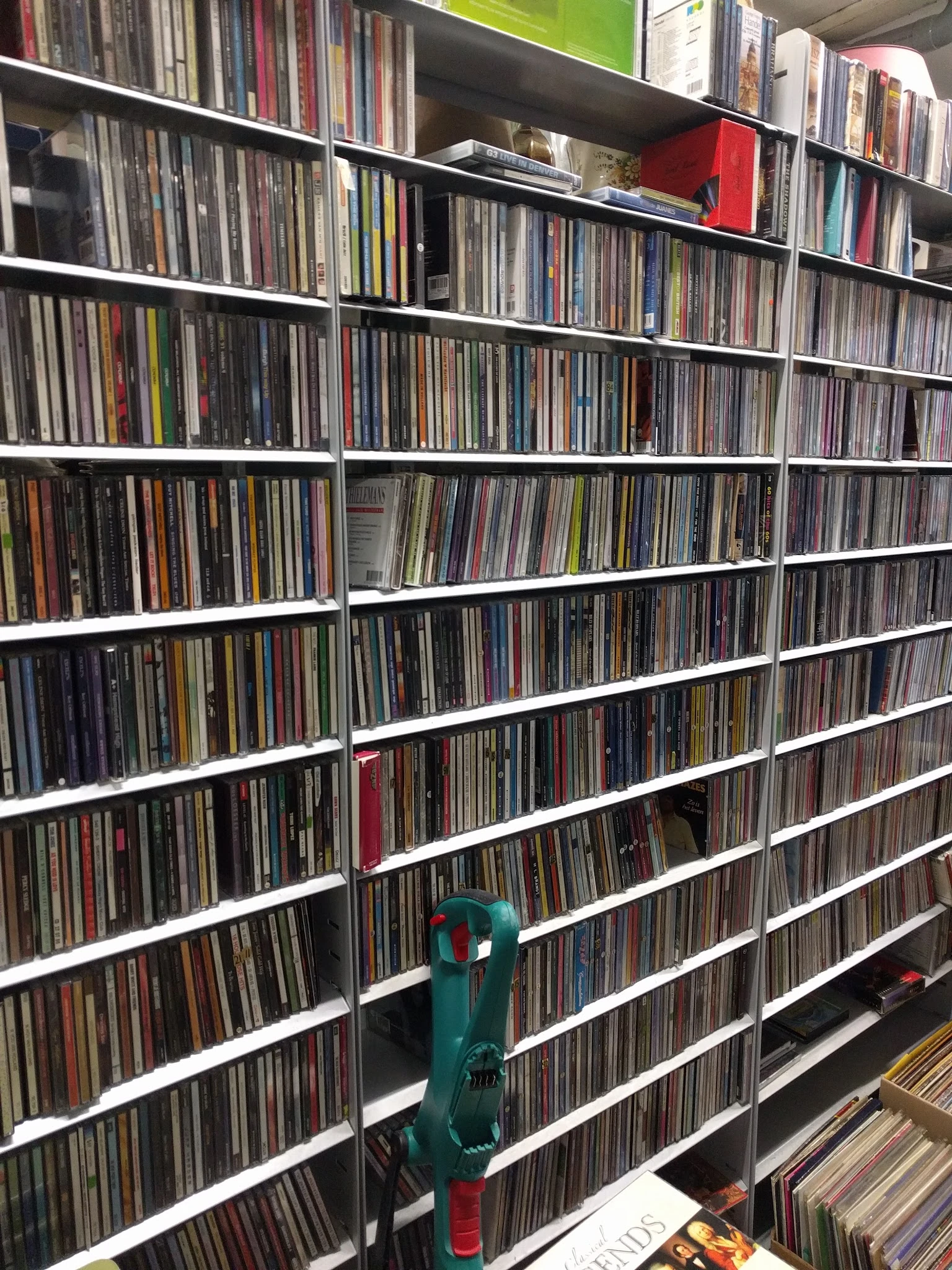 Witte stellingen vol met CDs en dvd's, netjes op rijen georganiseerd in een kringloopwinkel
