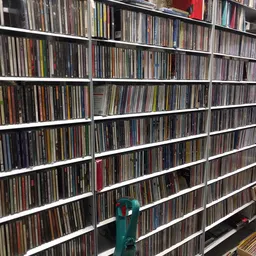 Witte stellingen vol met CDs en dvd's, netjes op rijen georganiseerd in een kringloopwinkel