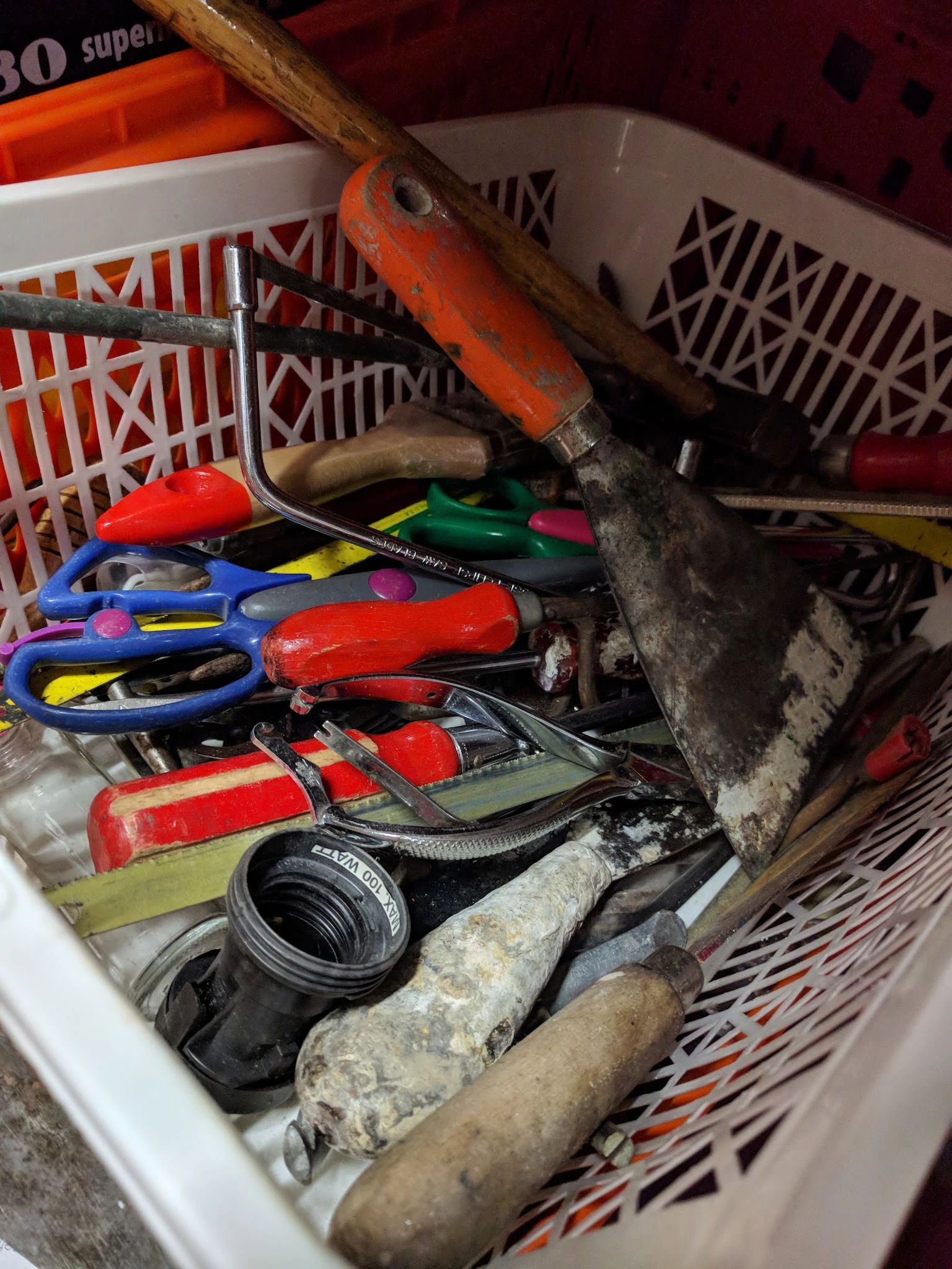 Verzameling gebruikt gereedschap en huishoudelijke spullen in een plastic krat
