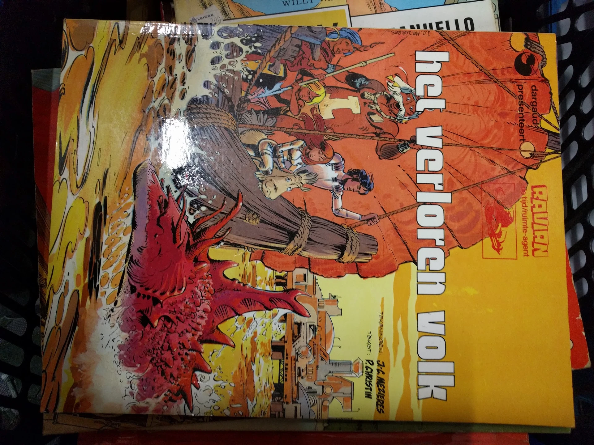 Tweedehands boeken en strips gestapeld op elkaar, waaronder een oranje boek met illustraties