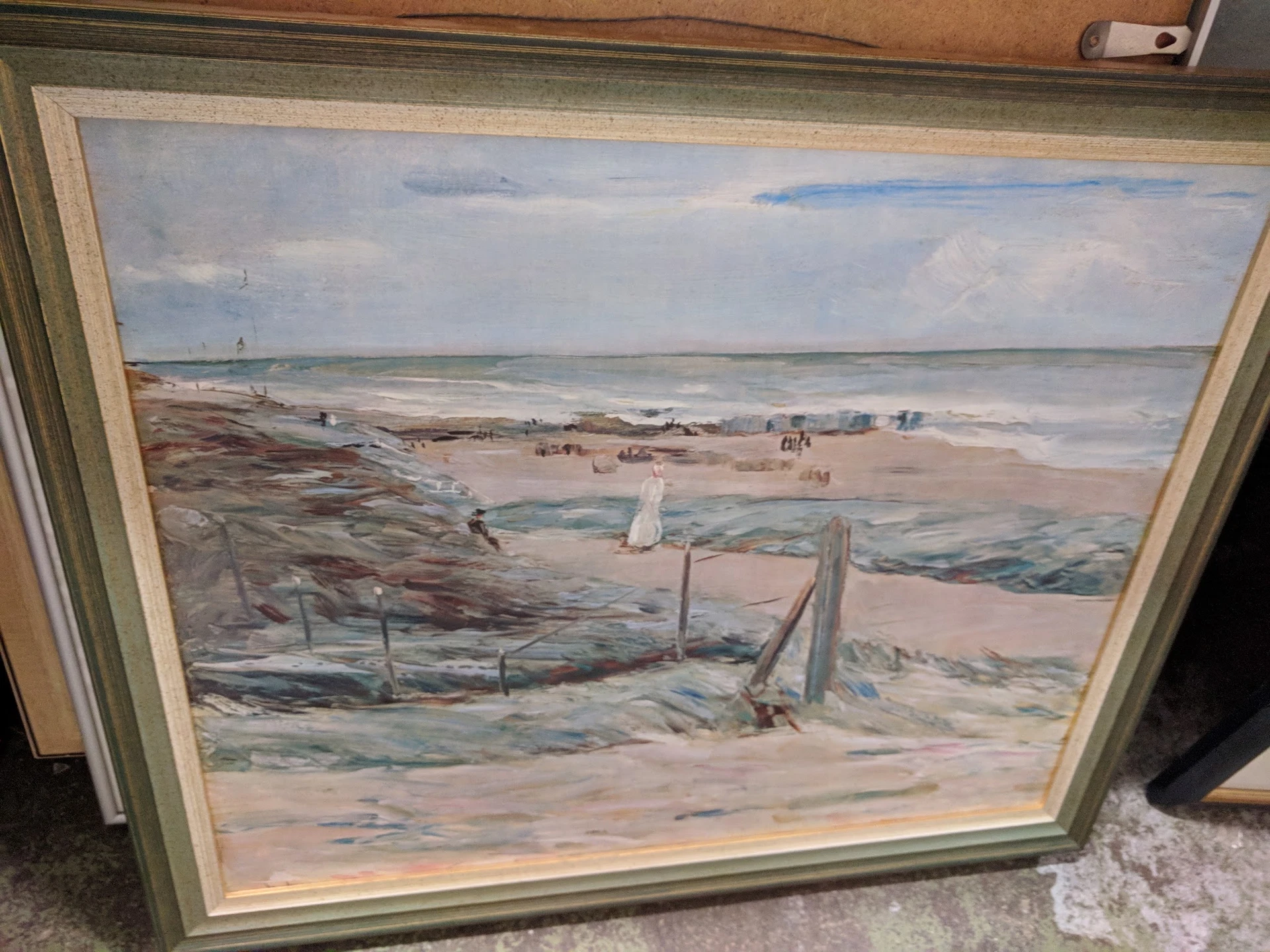 Ingelijste schilderij met strandtafereel met figuren en houten constructies