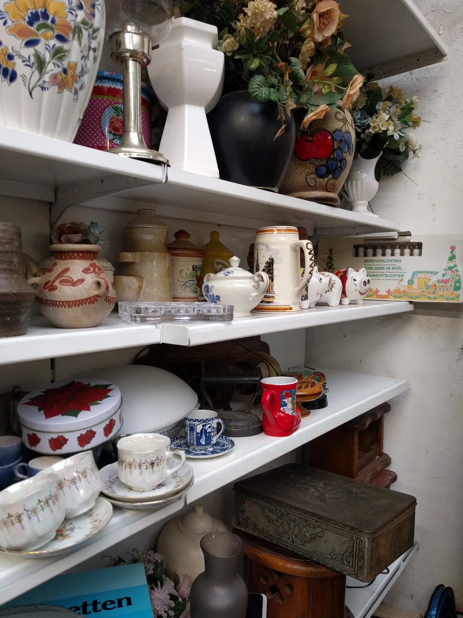 Witte stellingen met servies, keramiek en huishoudartikelen in een kringloopwinkel