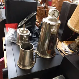 Glanzende RVS koffiepotten en thermoskannen op een tafel met diverse spullen