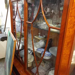 Antieke houten vitrinekast met glazen deuren en blauwe borden op display