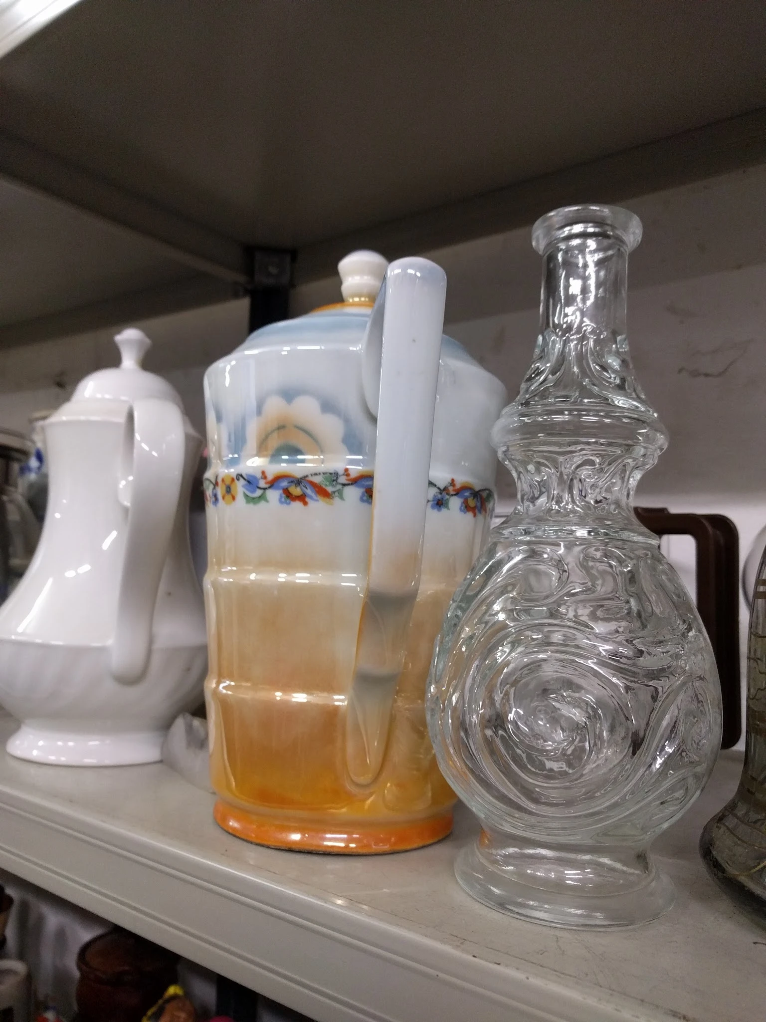 Verzameling vintage servies en glaskommen met decoratieve elementen op een plank