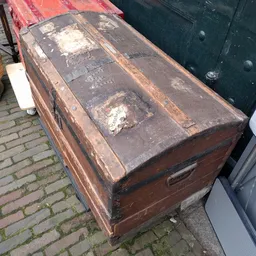 Oude bruine koffer met slijtage op bakstenen ondergrond
