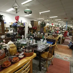 Winkelvloer met uitgestalde meubels, serviesgoed, lampen en decoratieve artikelen in een kringloopwinkel