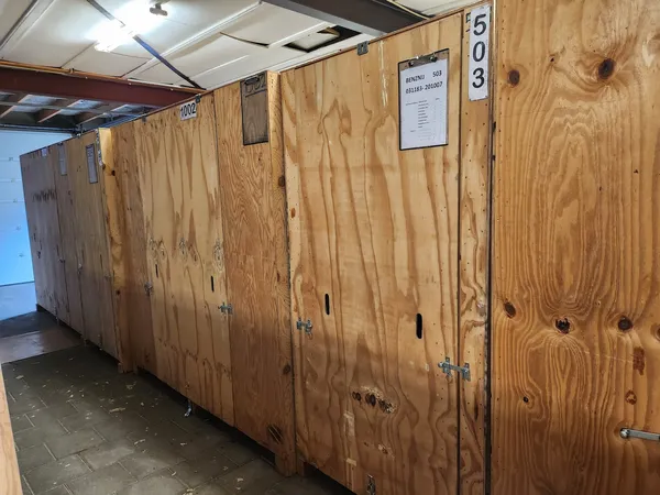 Houten opslagboxen en containersysteem in een kringloopwinkel met nummering aan de muren.