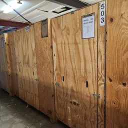 Houten opslagboxen en containersysteem in een kringloopwinkel met nummering aan de muren.