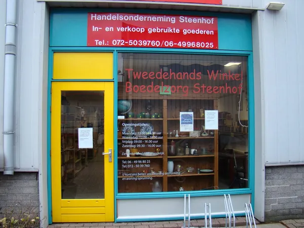 Winkelpui van tweedehands winkel met geel deur en turquoise frame, informatie op raam