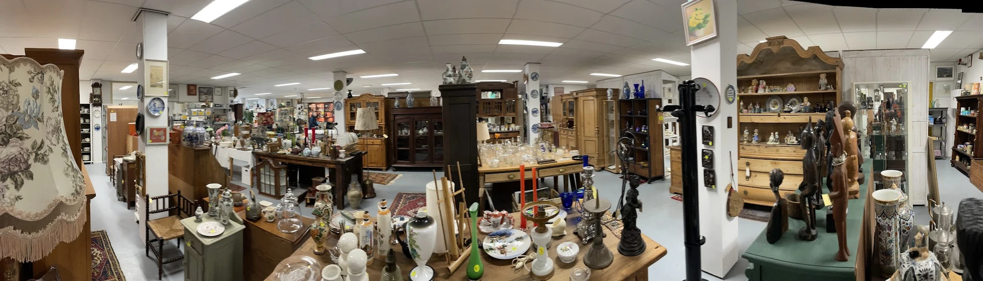 Overzicht van kringloopwinkel met diverse huishoudelijke artikelen, meubels en decoratieve spullen uitgestald