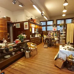 Ruim, licht winkelinterieur met houten vloer, diverse houten kasten, vitrines en uitgestalde curiosa en antieke spullen
