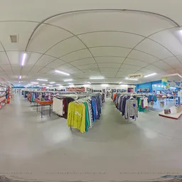 Ruim winkelinterieur met kledingrekken, stellingen met artikelen en diverse goederen verspreid over de vloer