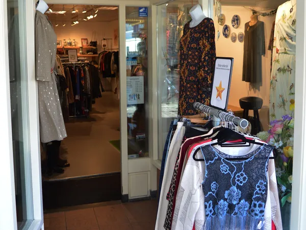 Winkelinterieur met kledingrekken, uitgestalde tweedehands kleding op hangers en mannequin in de winkel