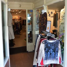 Winkelinterieur met kledingrekken, uitgestalde tweedehands kleding op hangers en mannequin in de winkel