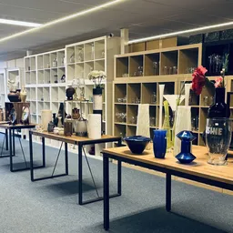Houten tafels met uitgestalde decoratieve artikelen: vazen, bloemen en accessoires in blauw en rood