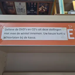 Oranje winkelplankje met Nederlands tekstbericht over DVD's en CD's niet meenemen