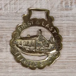 Bronzen medaille met afbeelding van een huis en tekst 'CREST & LAST' en 'LANDS END'