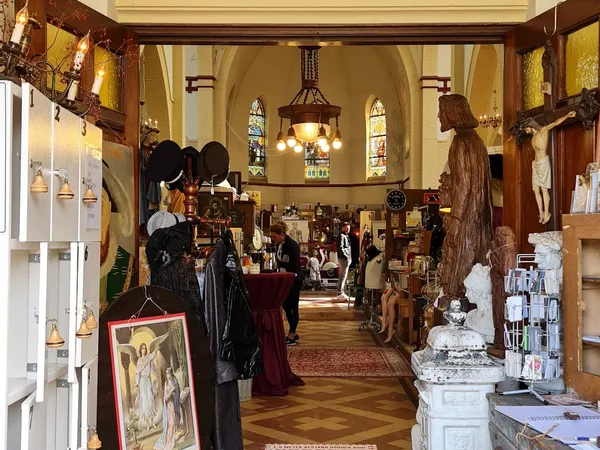 Ruim interieur van kringloopwinkel in voormalig kerkgebouw met stellingen vol spullen en beeldenwerk
