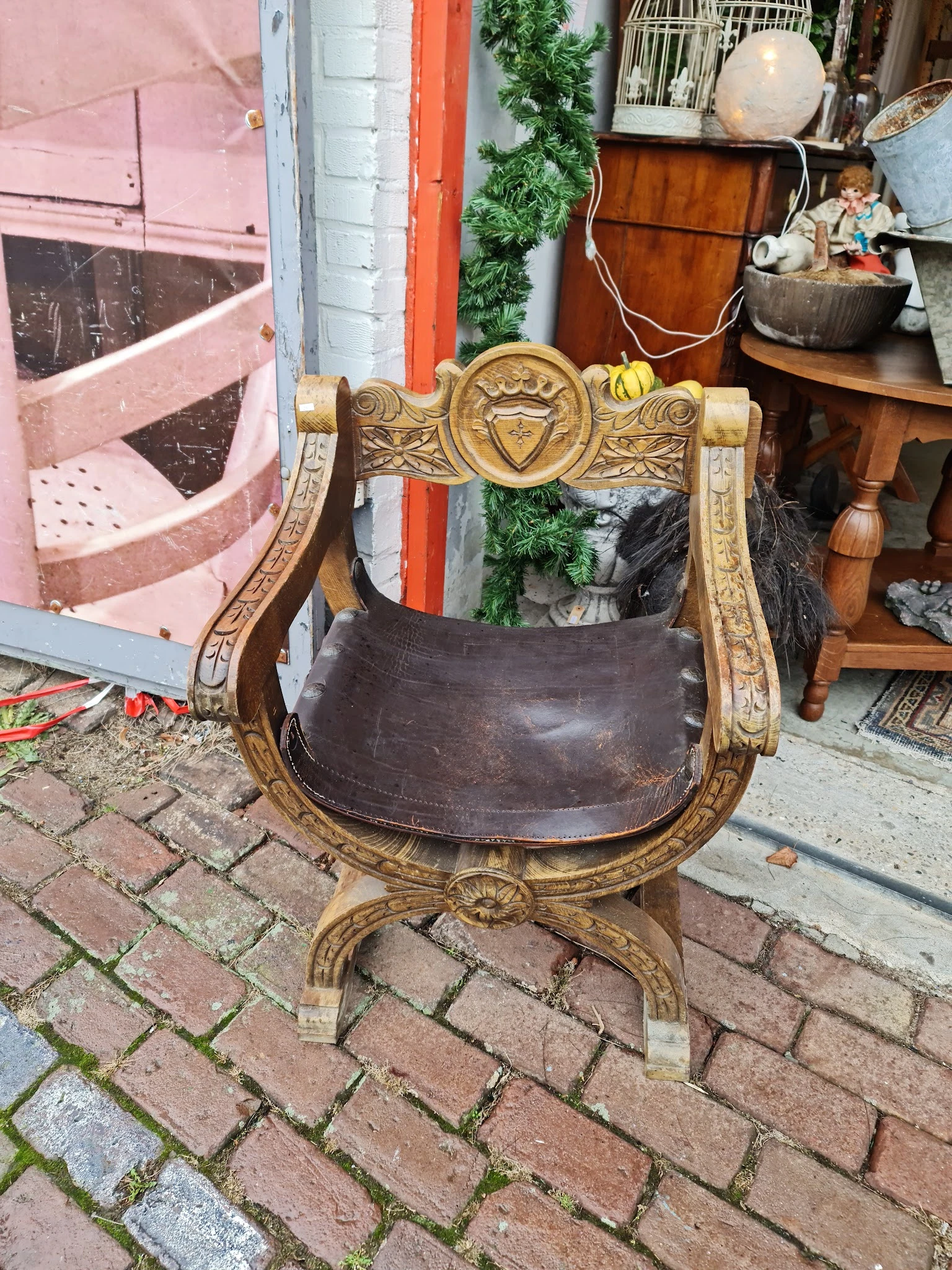 Antieke houten stoel met gesneden gouden armleuningen en bruinleren zitting
