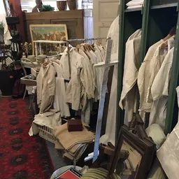 Rekken met witte en beige linnen kleding en textiel uitgestald in de winkel