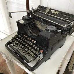Zwarte vintage typemachine met zichtbaar toetsenbord en papierrol op witte ondergrond