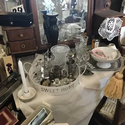 Uitgestalde vintage en antieke huishoudartikelen, glazen, servies en decoratieve items op een tafel