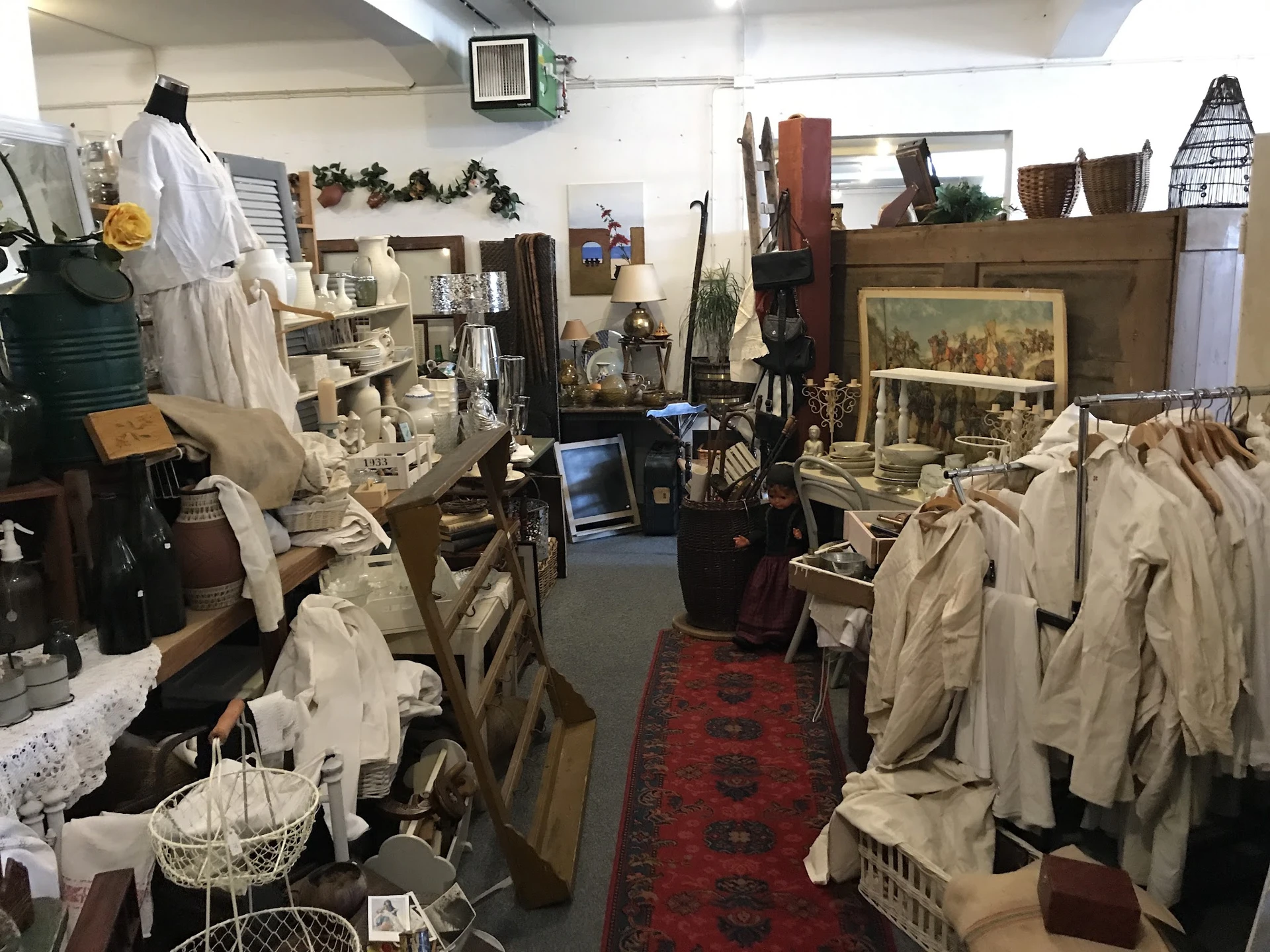 Winkelvloer van kringloopwinkel met rekken vol tweedehands kleding, meubels en huisraad