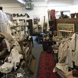 Winkelvloer van kringloopwinkel met rekken vol tweedehands kleding, meubels en huisraad