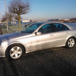 Zilvergrijze Mercedes sedan geparkeerd op een parkeerterrein bij water
