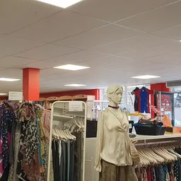Winkelvloer met kledingrekken, mannequins en vitrine in kringloopwinkel