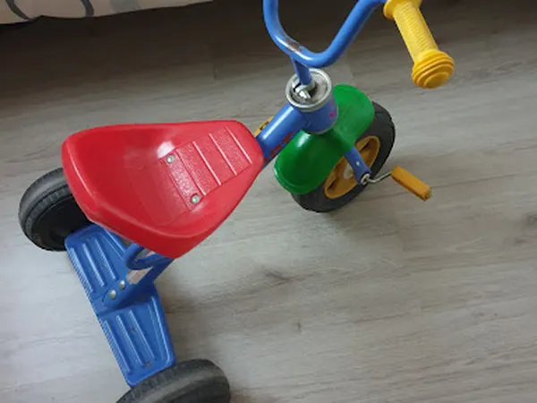 Rode en blauwe driewieler met gele trappen en groene wiel, speelgoedfiets voor kinderen