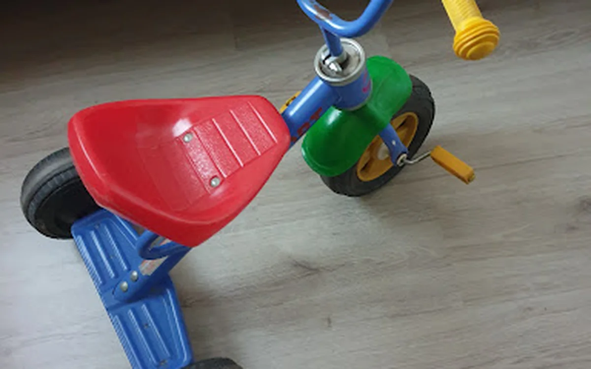 Rode en blauwe driewieler met gele trappen en groene wiel, speelgoedfiets voor kinderen