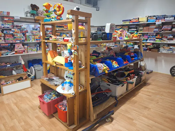 Winkelvloer met houten speelgoedorganizer, speelgoed op planken en in opbergboxen, stellingen met dozen vol artikelen op de a
