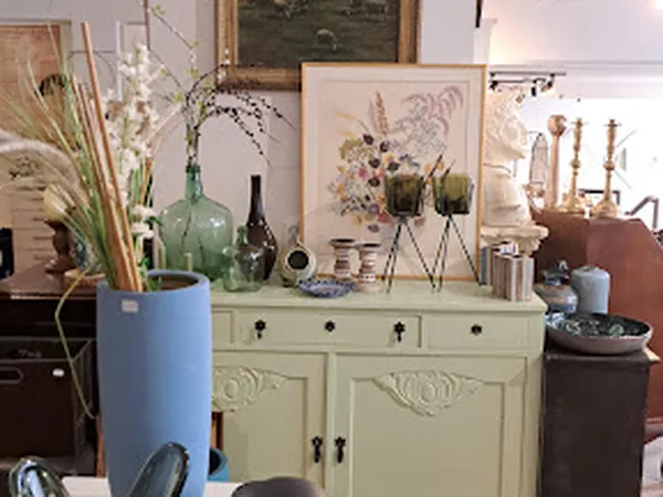 Vintage kast met fraaie decoratie: schilderijen, bloemen in vazen, glazen flesjes en diverse interieuraccessoires