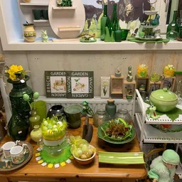 Uitgestalde groene en gele decoratieve items, plantenaccesoires en huishoudgoederen op schappen en tafels